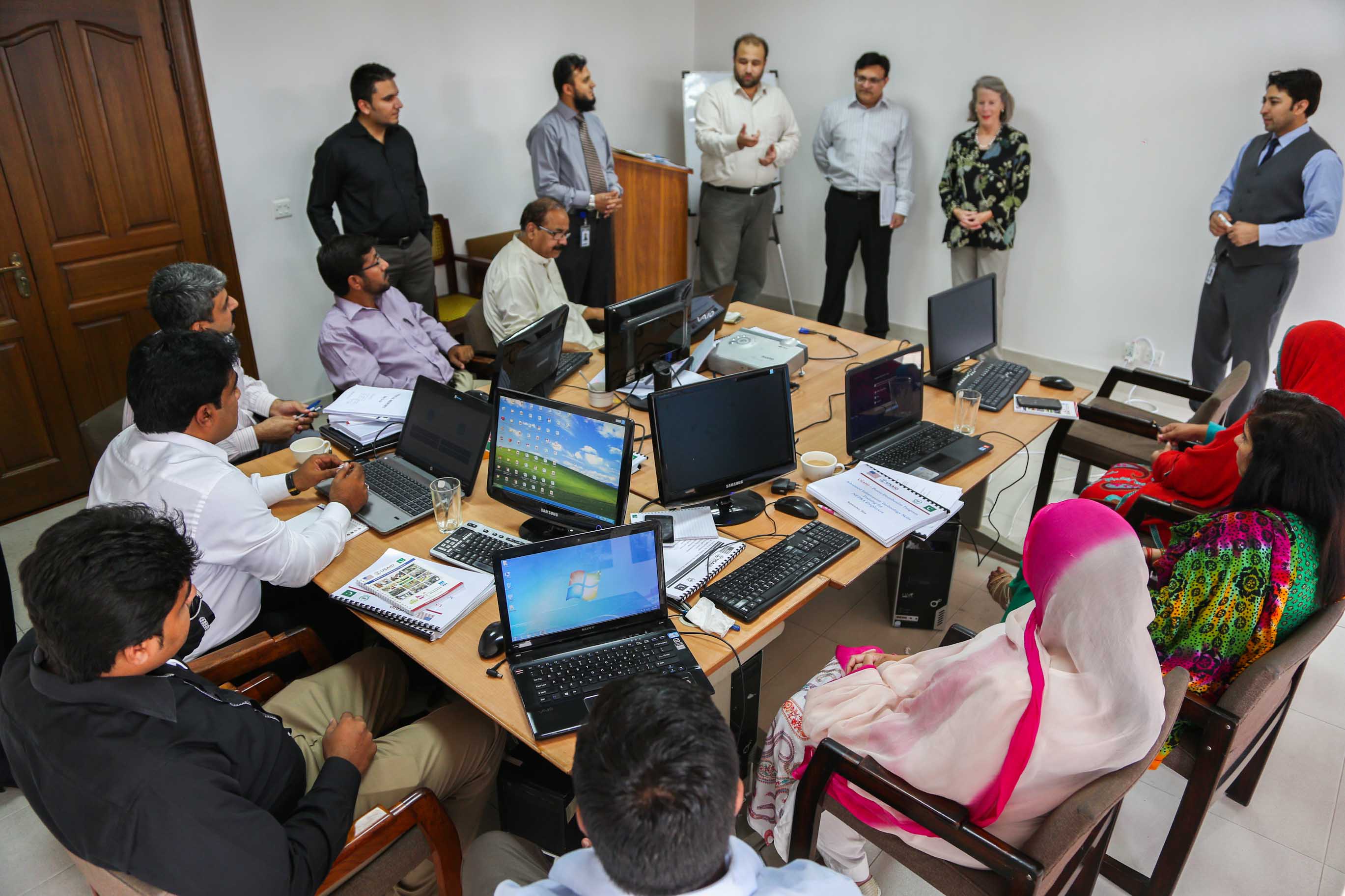 Employees taking part in a computer skills training session around a conference table.